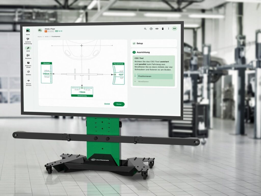 Specialist is Wearing a Virtual Reality Headset and Holding Two Joysticks in a Car Service. Mechanic is Investigating the Breakdown with the Help of Future Technology. Repairman in Modern Workshop.